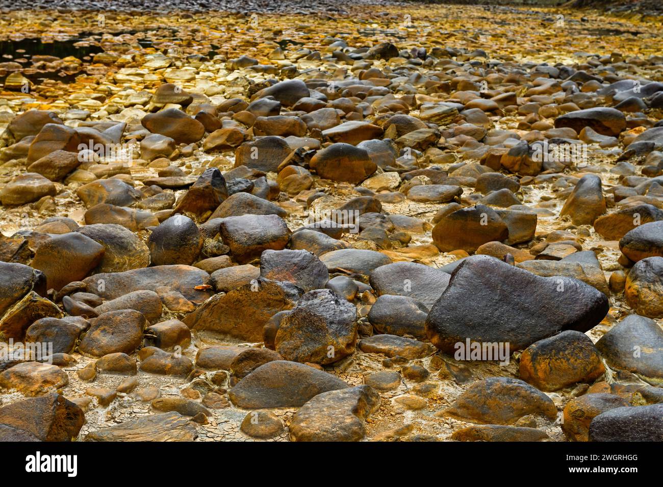 Une vue rapprochée des roches jaunâtres couvertes de soufre dans le lit de la rivière Rio Tinto sous un ciel brumeux Banque D'Images