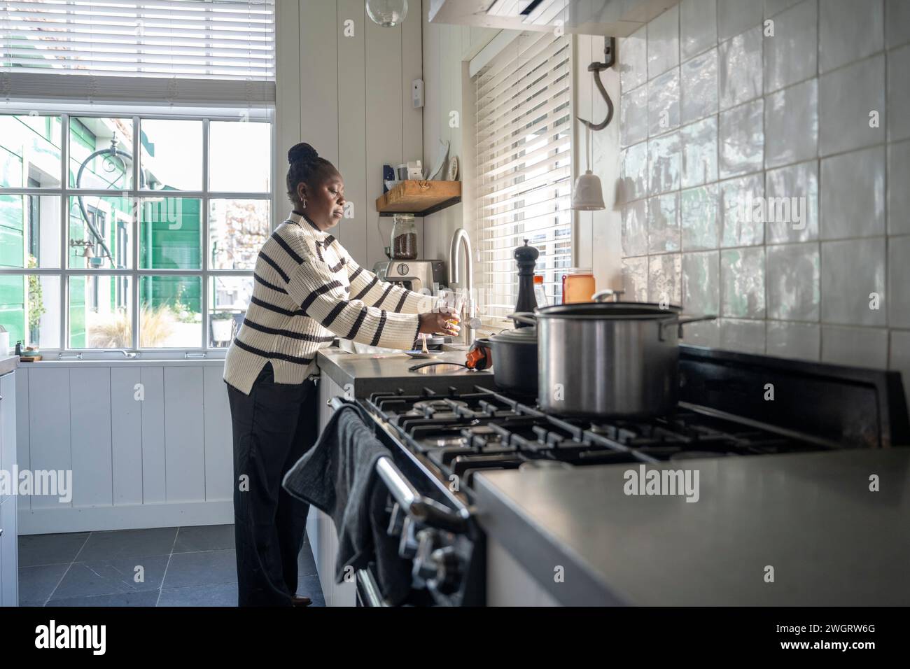 Femme nettoyant sa cuisine chargeant le lave-vaisselle Banque D'Images