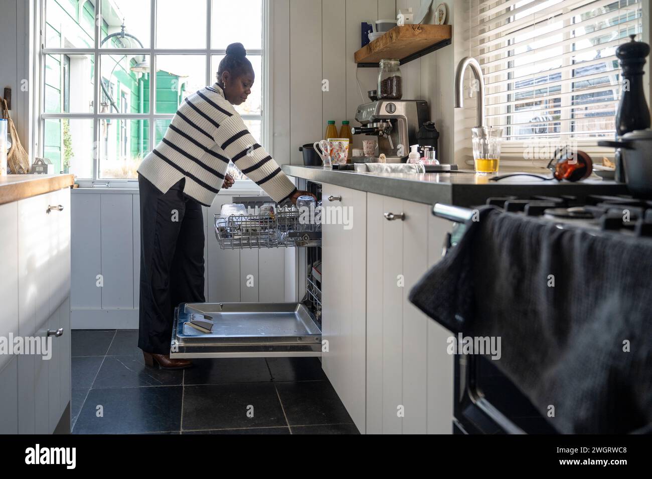 Femme nettoyant sa cuisine chargeant le lave-vaisselle Banque D'Images