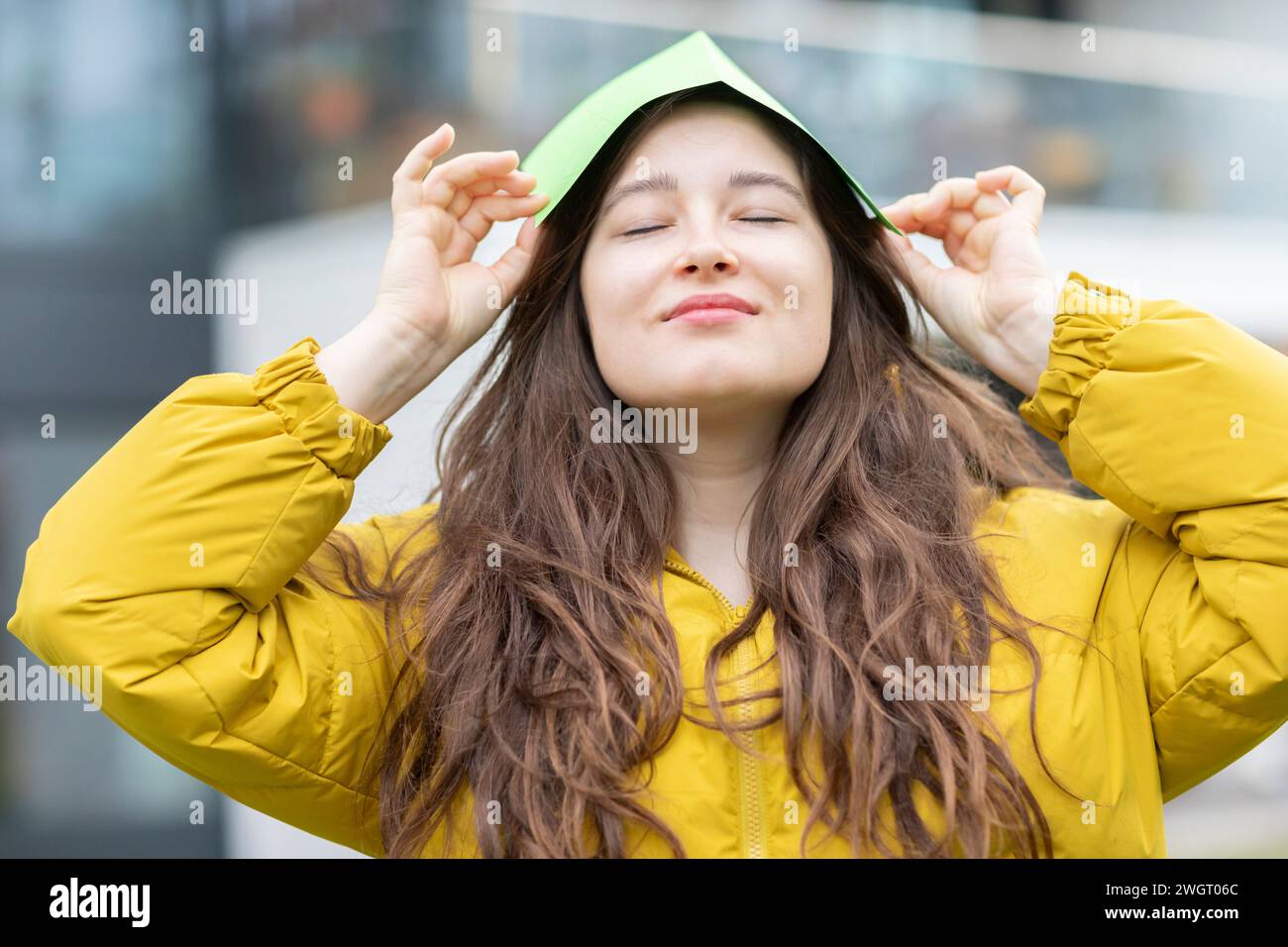 jeune femme avec toit de papier vert comme protection climatique à l'extérieur Banque D'Images