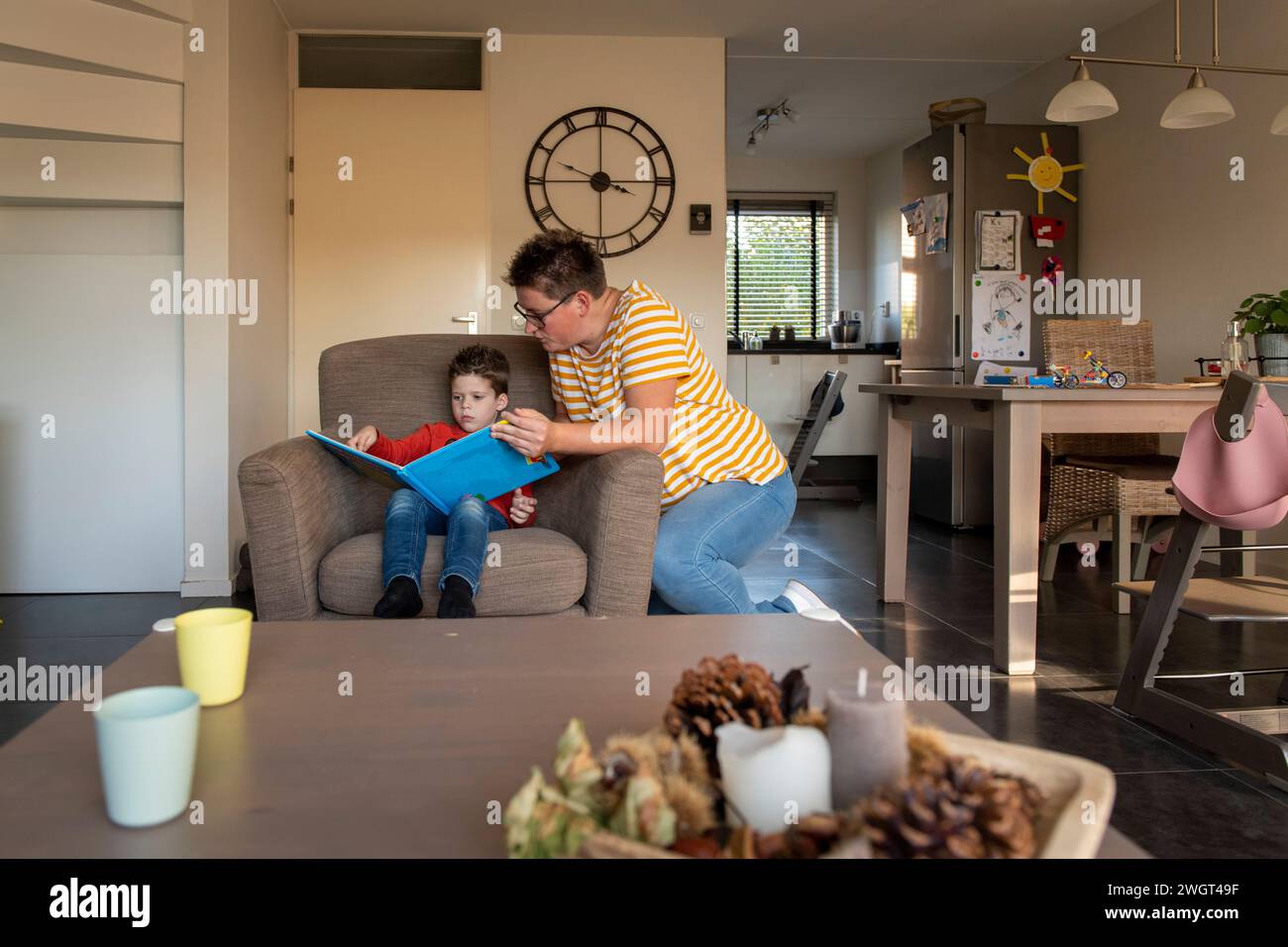 Mère aidant son fils avec ses devoirs assis dans leur salon Banque D'Images