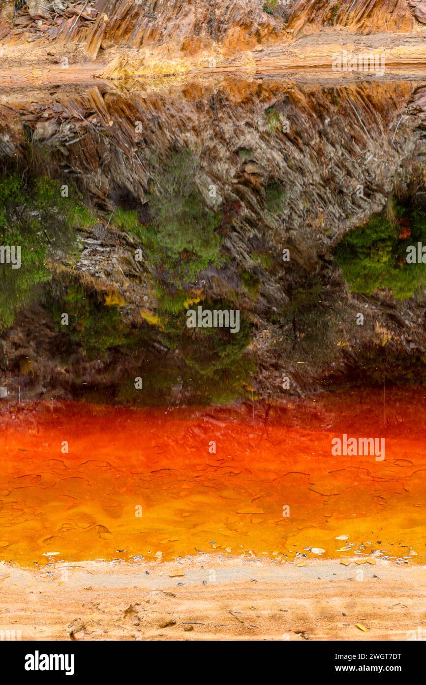 Des couches de terre frappantes et une strie vive d'eau rouge bordent le sol fissuré du Rio Tinto Banque D'Images