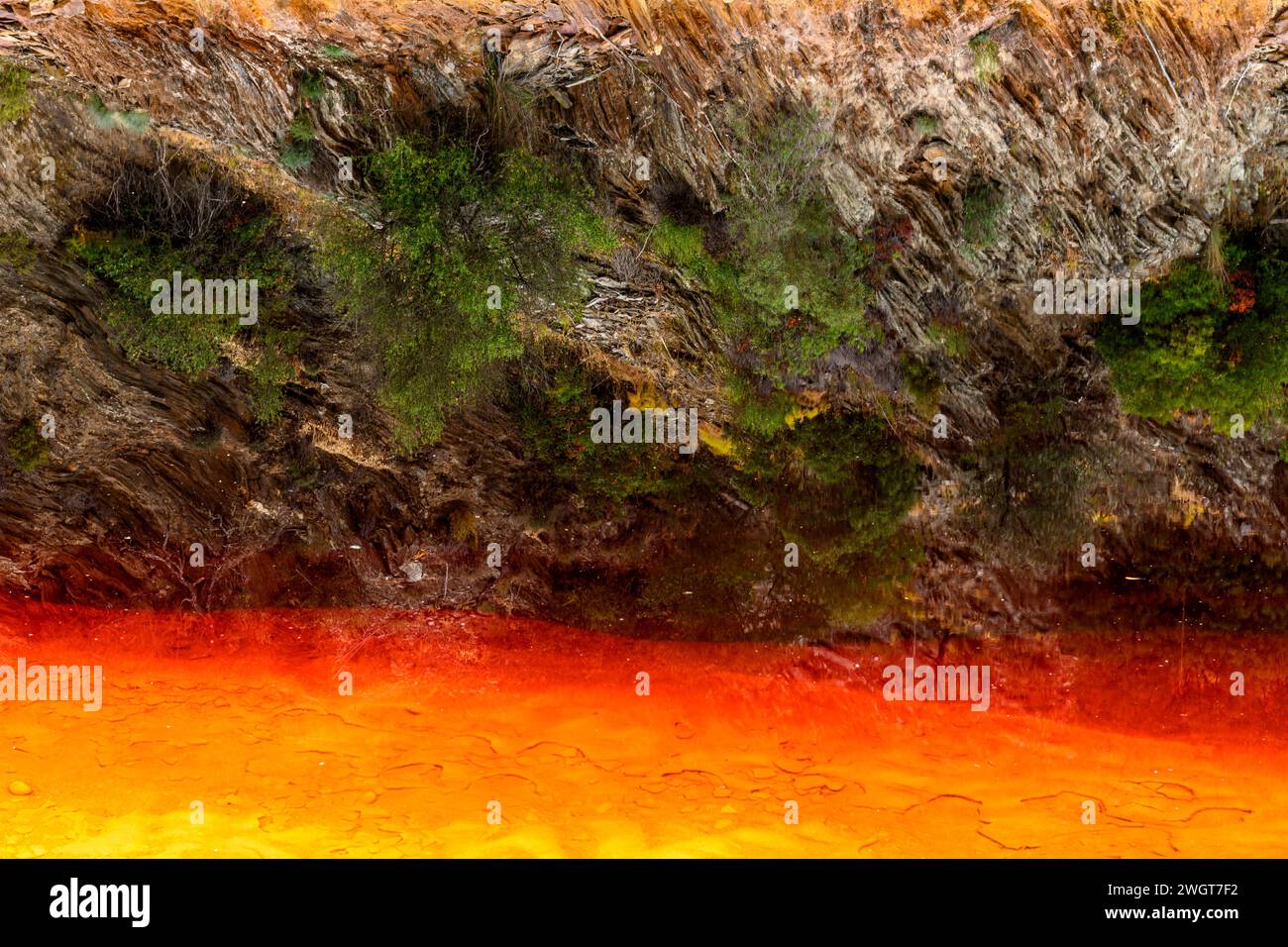 Des couches de terre frappantes et une strie vive d'eau rouge bordent le sol fissuré du Rio Tinto Banque D'Images