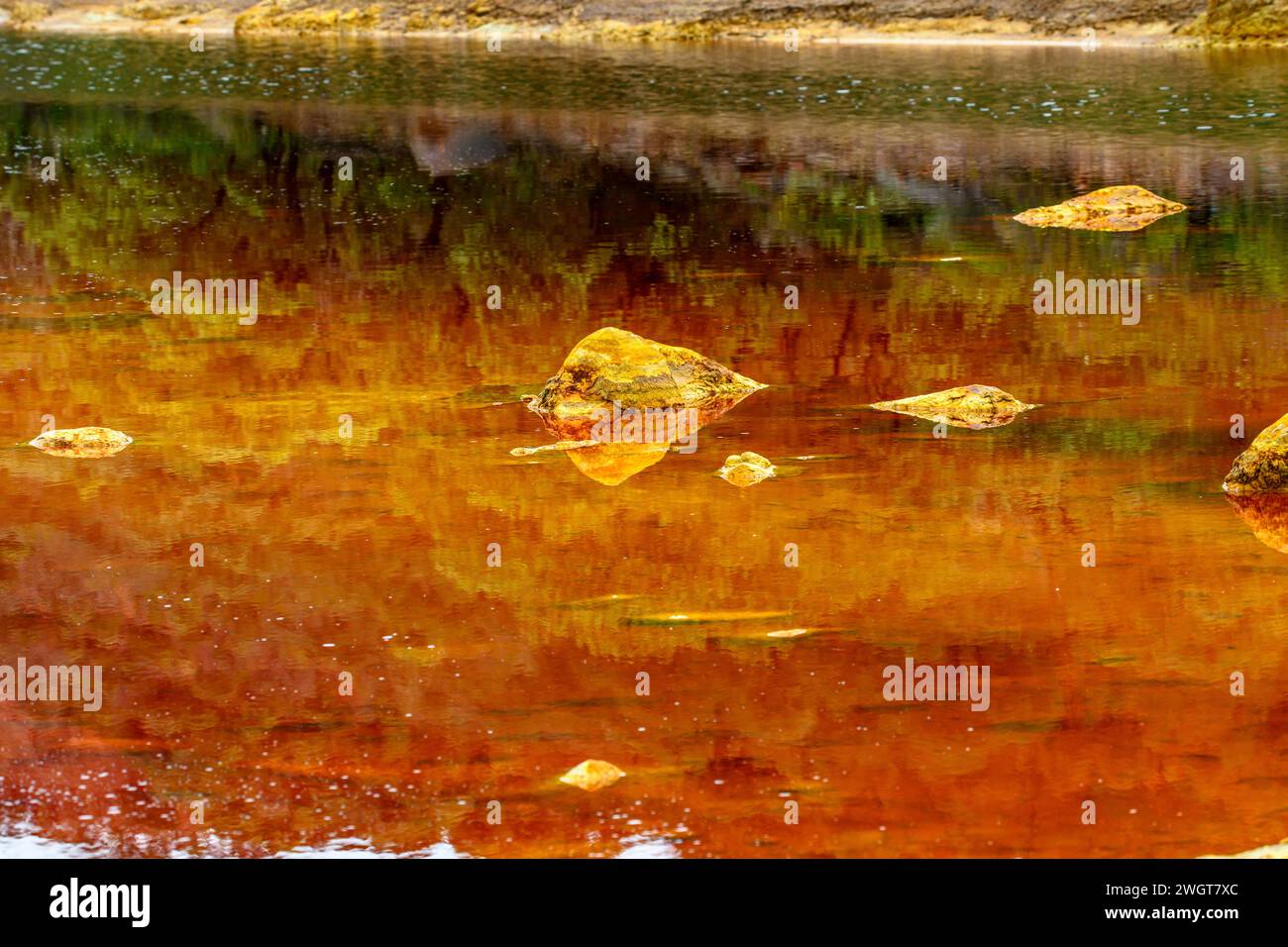 Des couches de terre frappantes et une strie vive d'eau rouge bordent le sol fissuré du Rio Tinto Banque D'Images