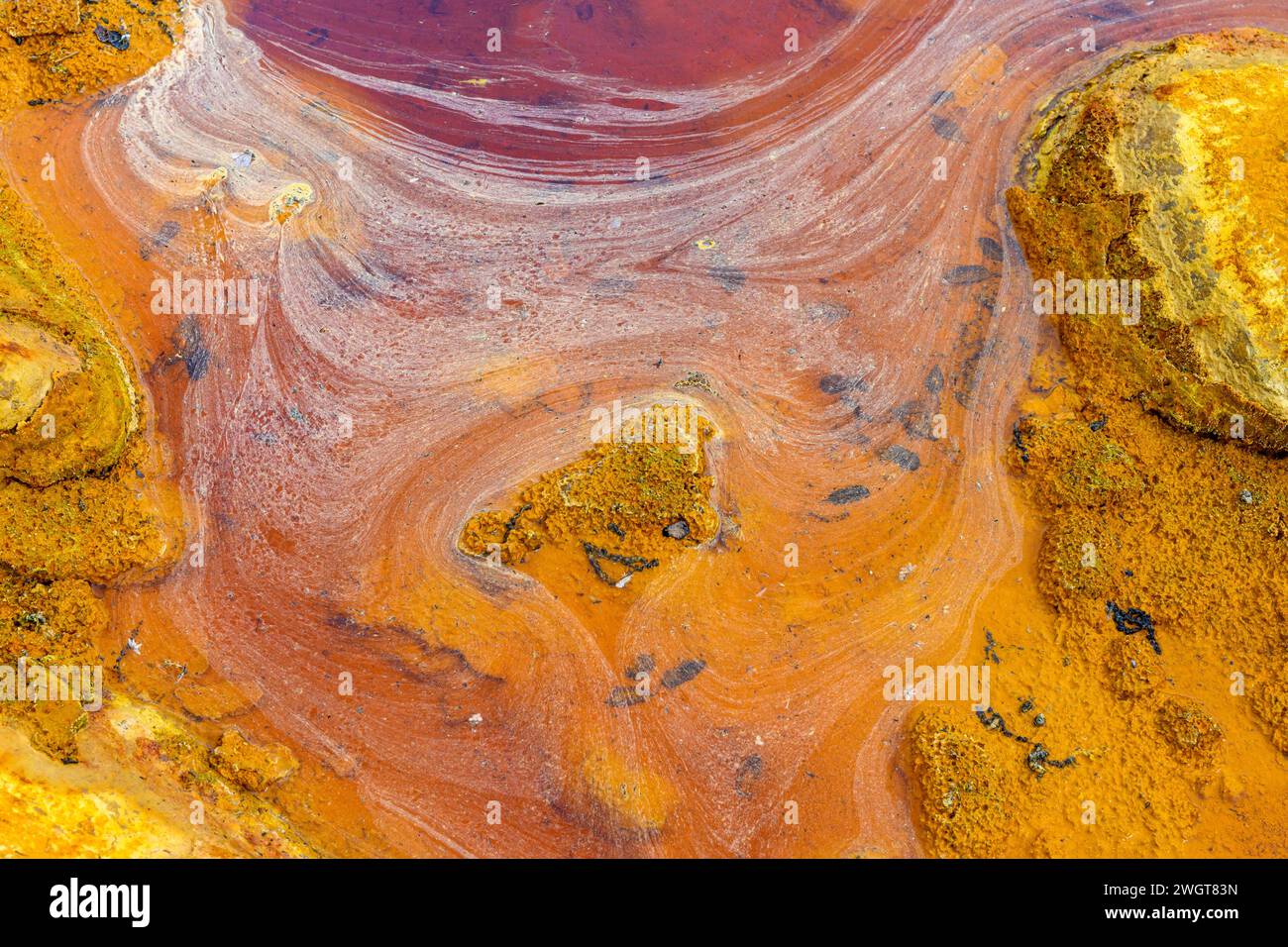 Des couches de terre frappantes et une strie vive d'eau rouge bordent le sol fissuré du Rio Tinto Banque D'Images