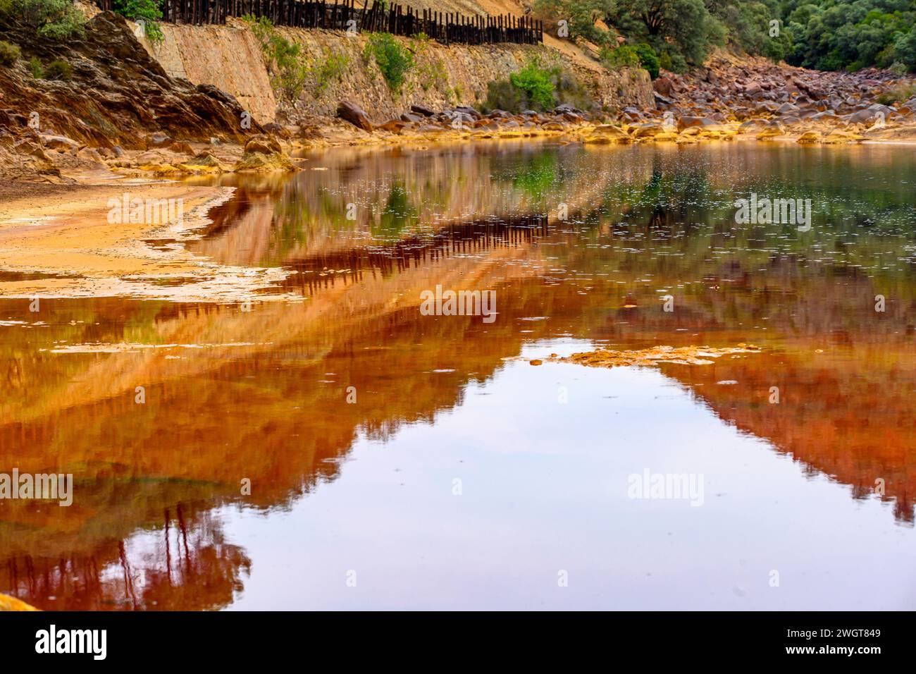 Des couches de terre frappantes et une strie vive d'eau rouge bordent le sol fissuré du Rio Tinto Banque D'Images