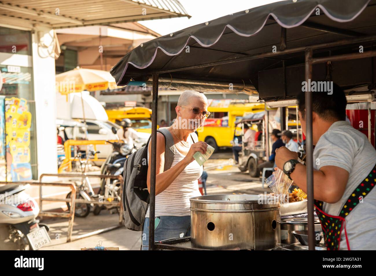 Femme mi-âgée voyageuse solo s'arrête pour acheter de la nourriture de rue à un vendeur à Chiang mai. Thaïlande Banque D'Images