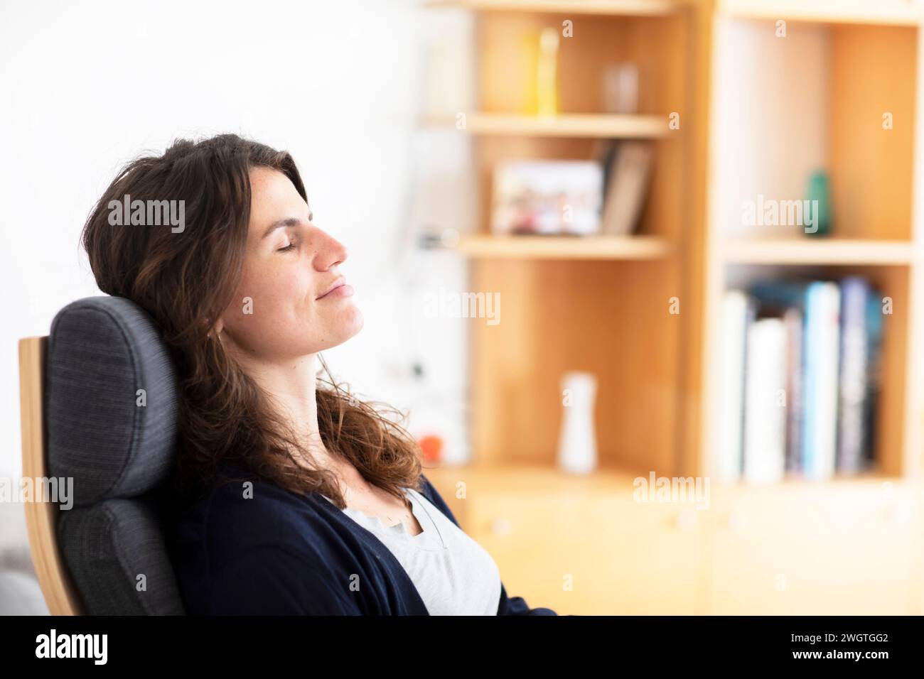 Jeune femme assise à la maison, profitant du moment Banque D'Images