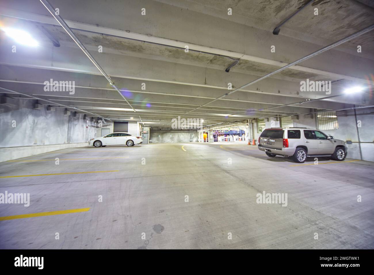 Garage couvert clairsemé avec lumières vives et deux voitures Banque D'Images