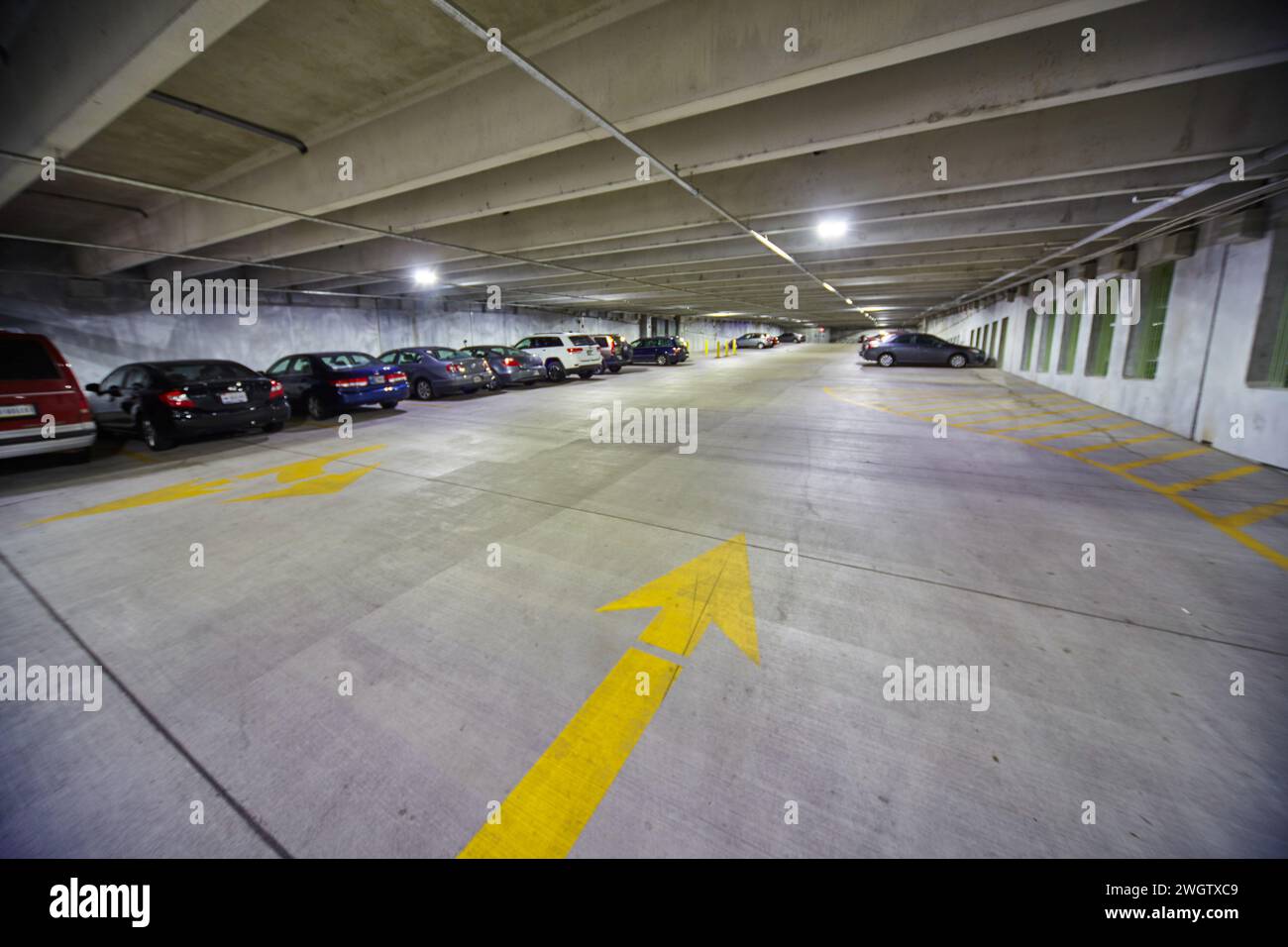 Flèches jaunes vives dans le garage de stationnement avec lumières fluorescentes - vue au sol Banque D'Images