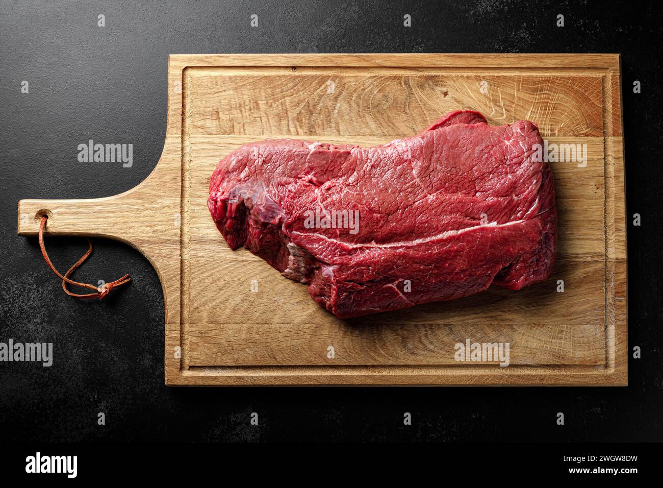 Entrecote de viande de boeuf sur une planche à découper, filet de viande de boeuf crue sur fond noir, vue de dessus Banque D'Images