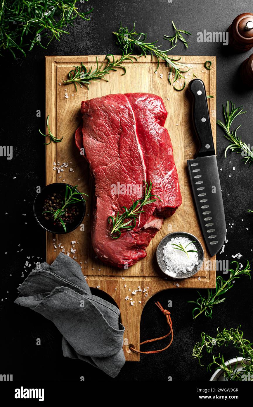 Entrecote de viande de boeuf sur une planche à découper, filet de viande de boeuf crue sur fond noir, vue de dessus Banque D'Images