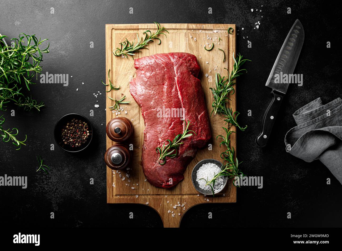 Entrecote de viande de boeuf sur une planche à découper, filet de viande de boeuf crue sur fond noir, vue de dessus Banque D'Images