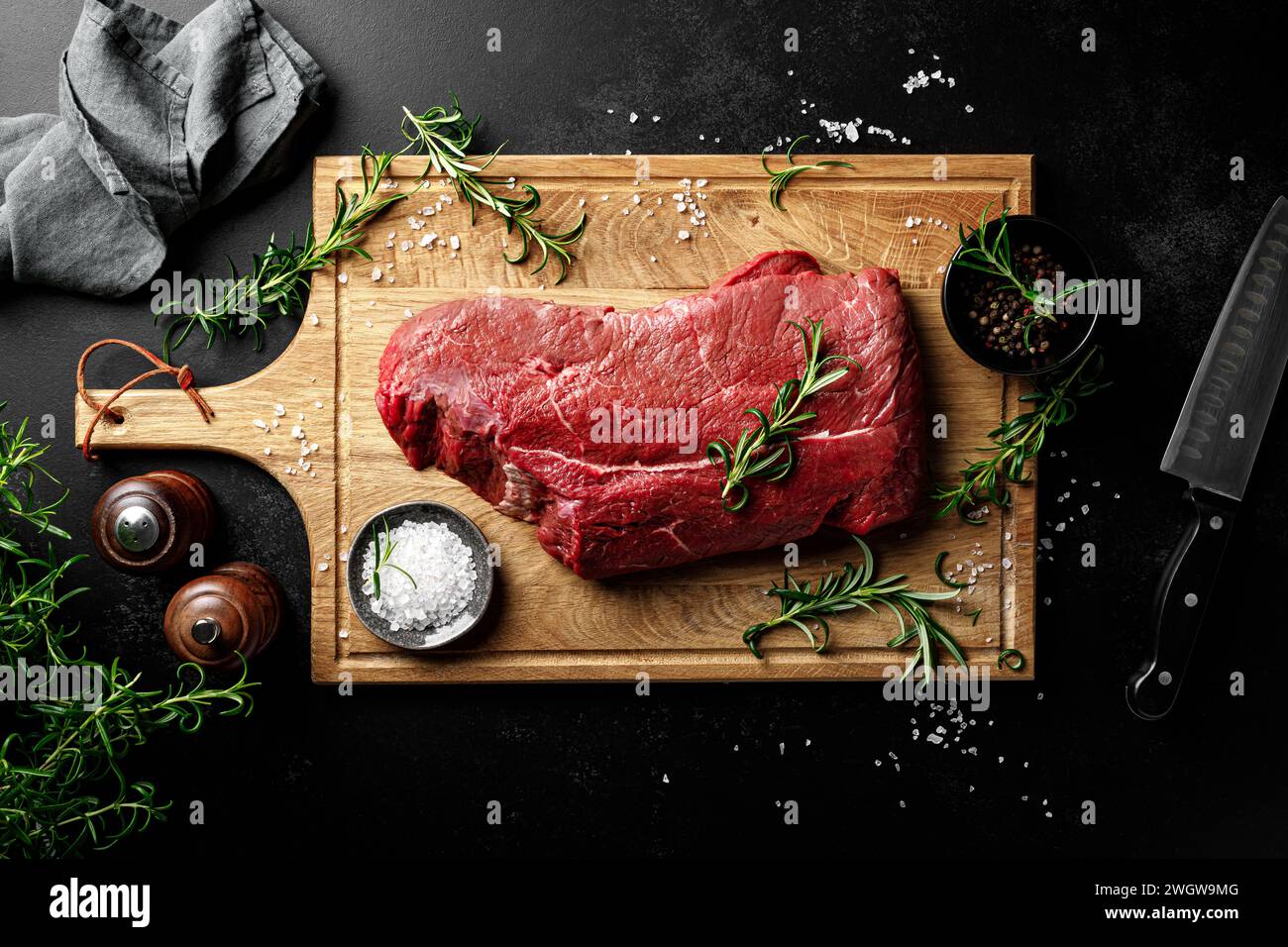 Entrecote de viande de boeuf sur une planche à découper, filet de viande de boeuf crue sur fond noir, vue de dessus Banque D'Images