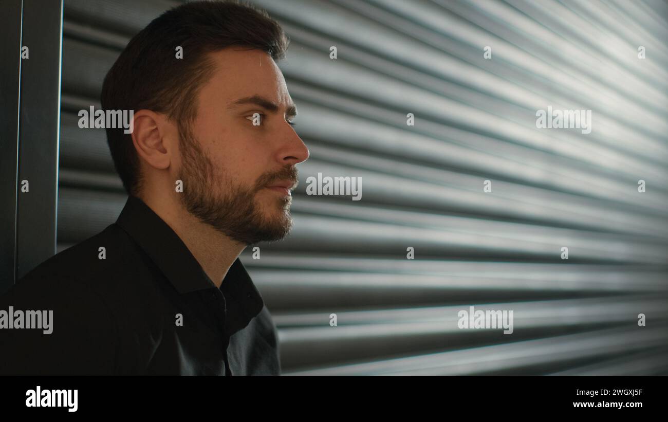 Vue de côté sérieux homme caucasien réfléchi entrepreneur d'affaires vendeur au détail directeur exécutif homme d'affaires pensif homme d'affaires mec masculin sur le mur noir Banque D'Images