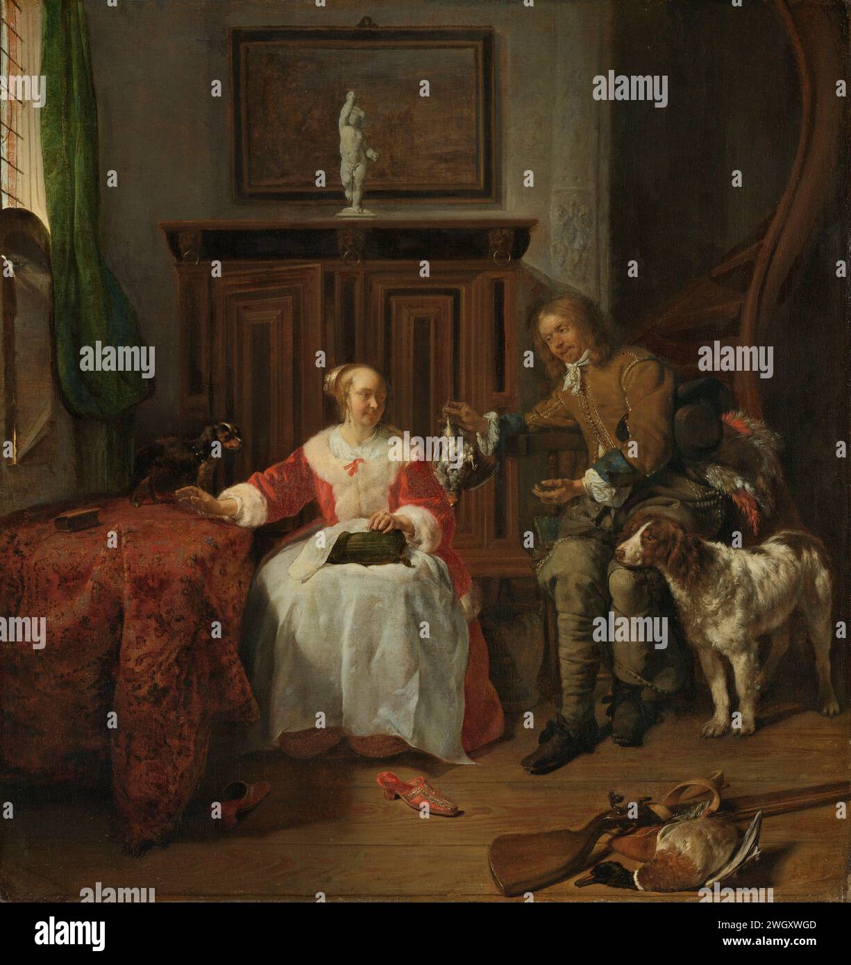 Le cadeau du chasseur, Gabriël Metsu, c. 1658 - c. 1661 peinture le don du Jager. Intérieur avec un chasseur qui tient une perdrix pour une femme assise qui travaille à la couture. En plus de l'homme un grand chien de chasse. Il y a un petit chien sur la table avec la femme. En arrière-plan un placard avec une statue de Cupido. Un tableau sur le mur. Au premier plan un fusil de chasse et un canard mort. Sur la droite un escalier en colimaçon. toile. la peinture à l'huile (peinture) revient de la chasse. chasseur affichant ou présentant le butin de la chasse. intérieur de la maison. couture maison ; réparation de vêtements. ornement Banque D'Images