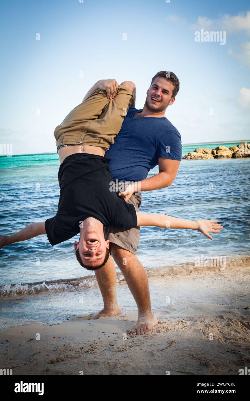 Deux jeunes hommes qui s'amusent sur la plage, Bahamas Banque D'Images