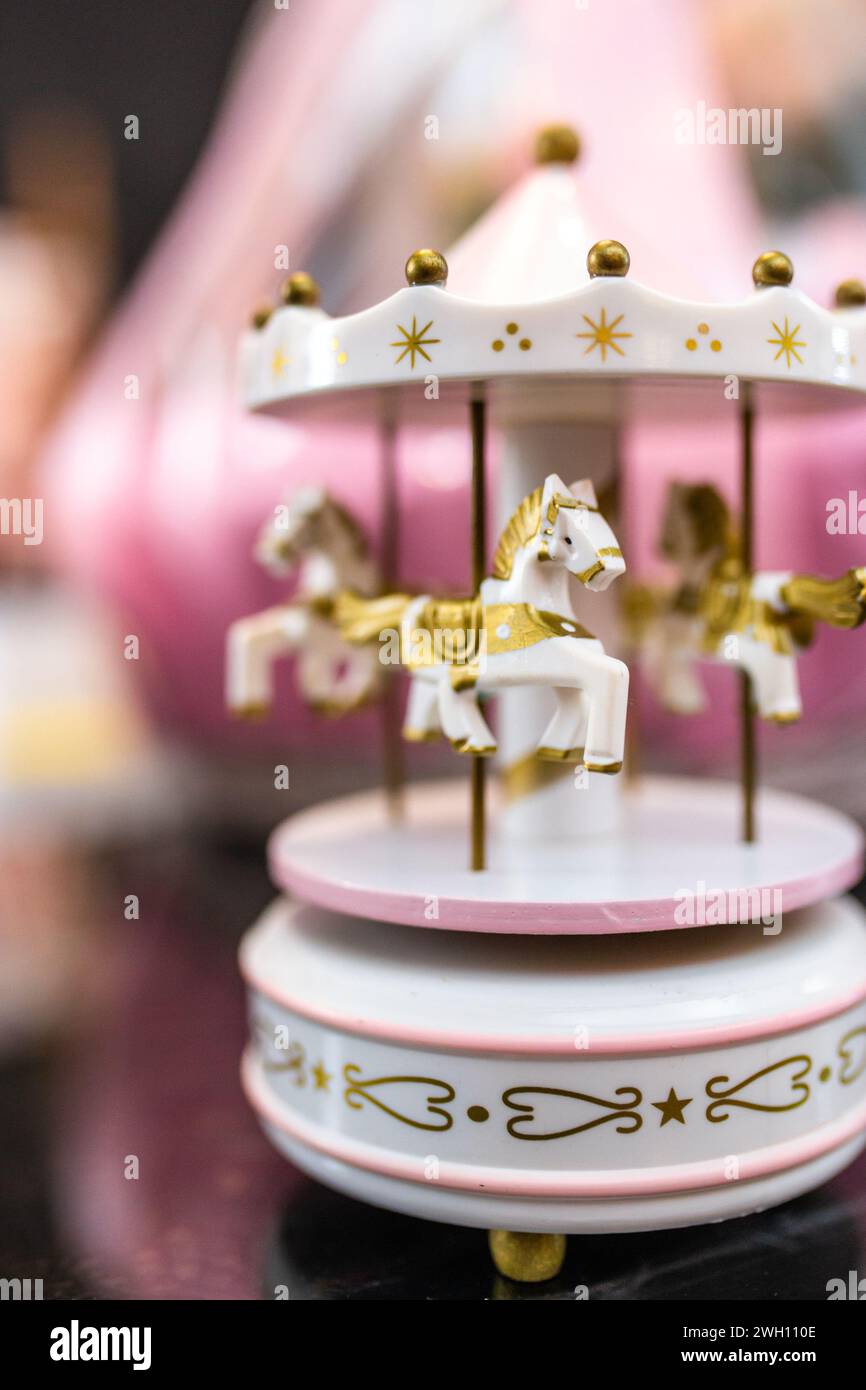 Un beau carrousel de musique blanc et rose avec des chevaux dorés isolés sur un fond sombre, parfait pour votre prochain projet. Créez une atmosphère magique f Banque D'Images