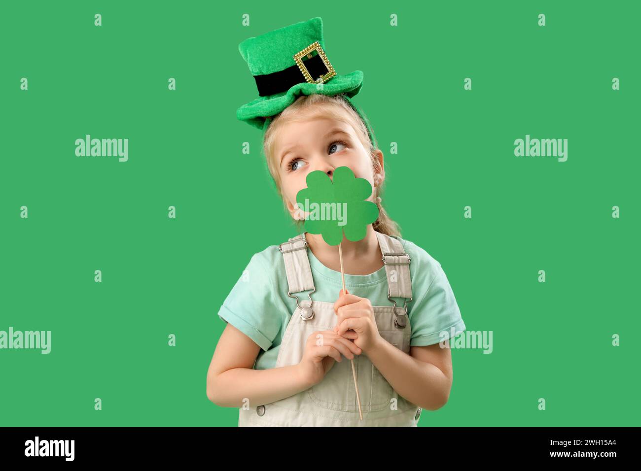 Mignonne petite fille avec chapeau de leprechaun et trèfle en papier sur fond vert. Prog Célébration de la fête de Patrick Banque D'Images