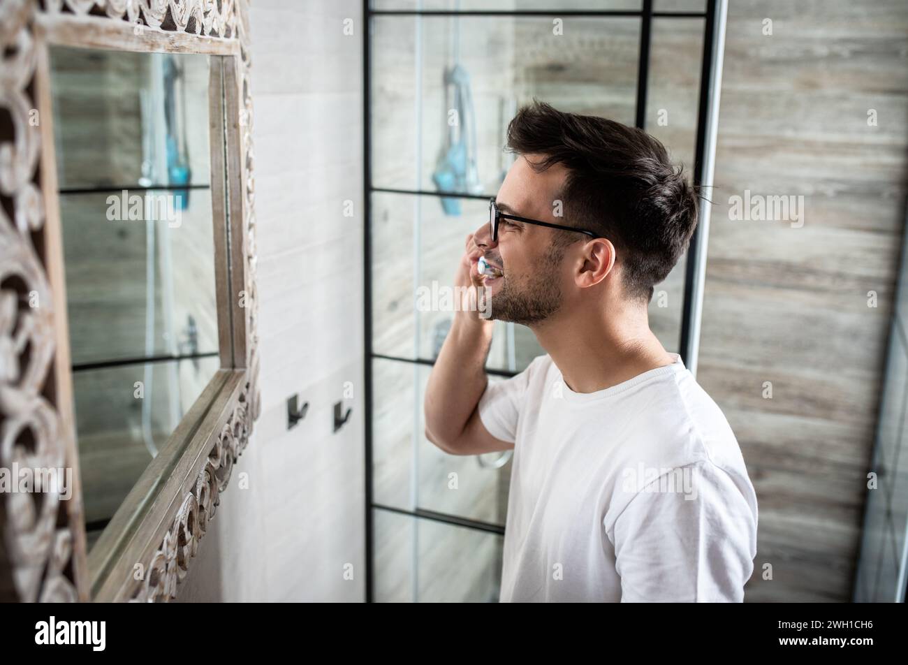 Homme passant par la routine matinale dans la salle de bain se brossant les dents. Banque D'Images