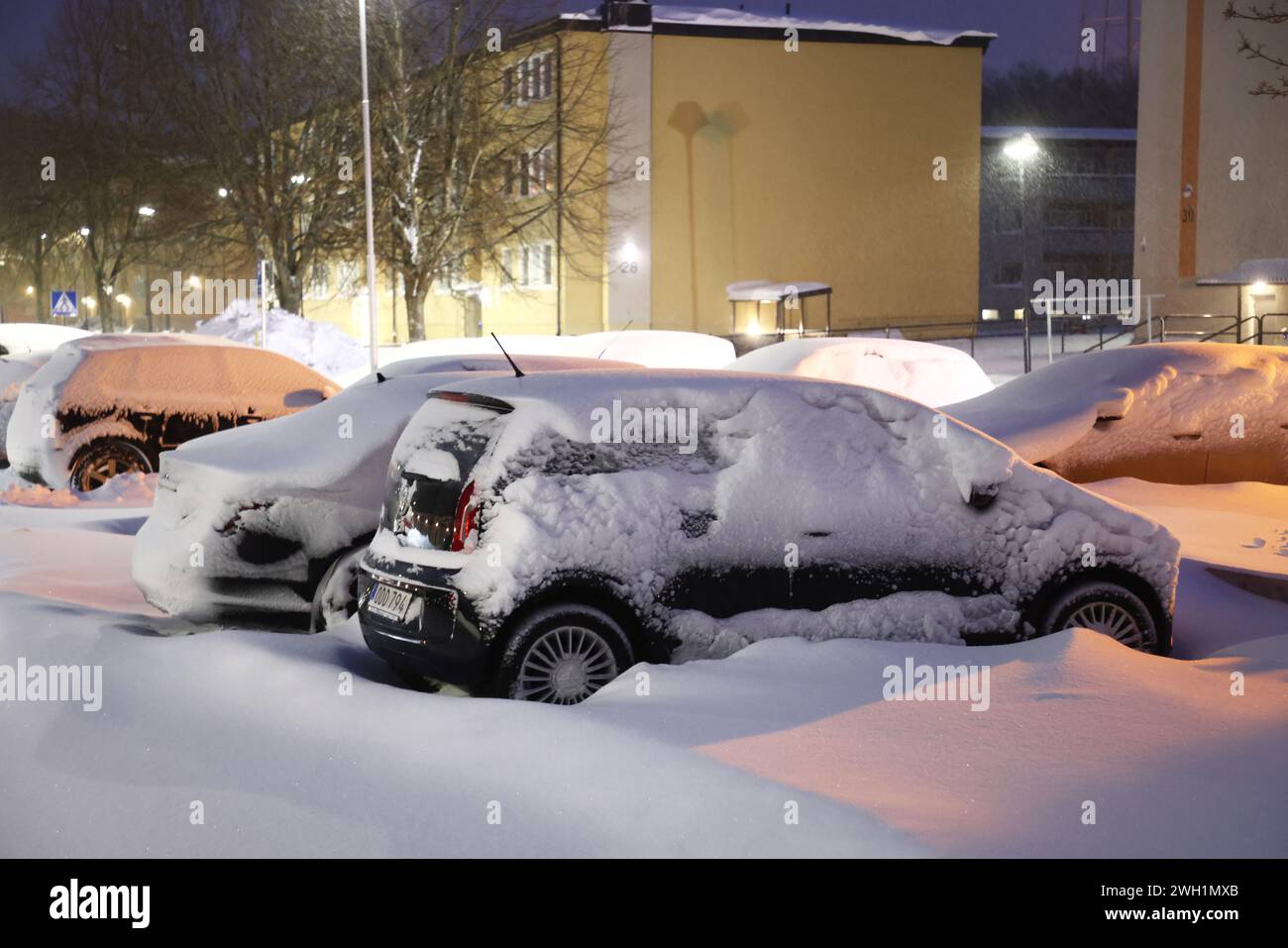 Météo saisonnière, fortes chutes de neige sur le comté de Östergötland, Suède, mercredi matin. Voitures enneigées sur un parking dans un quartier résidentiel. Banque D'Images