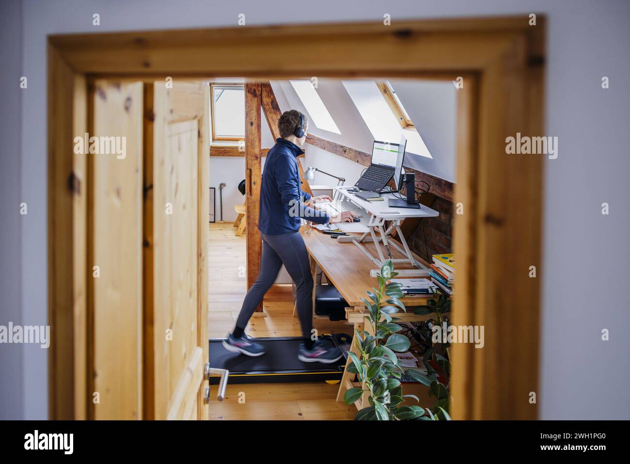 Eine Frau laeuft waehrend der Arbeit zu Hause im Home Office an ihrem Schreibtisch auf einem Walking Pad. Berlin, 07.02.2024. Berlin Deutschland *** A Banque D'Images
