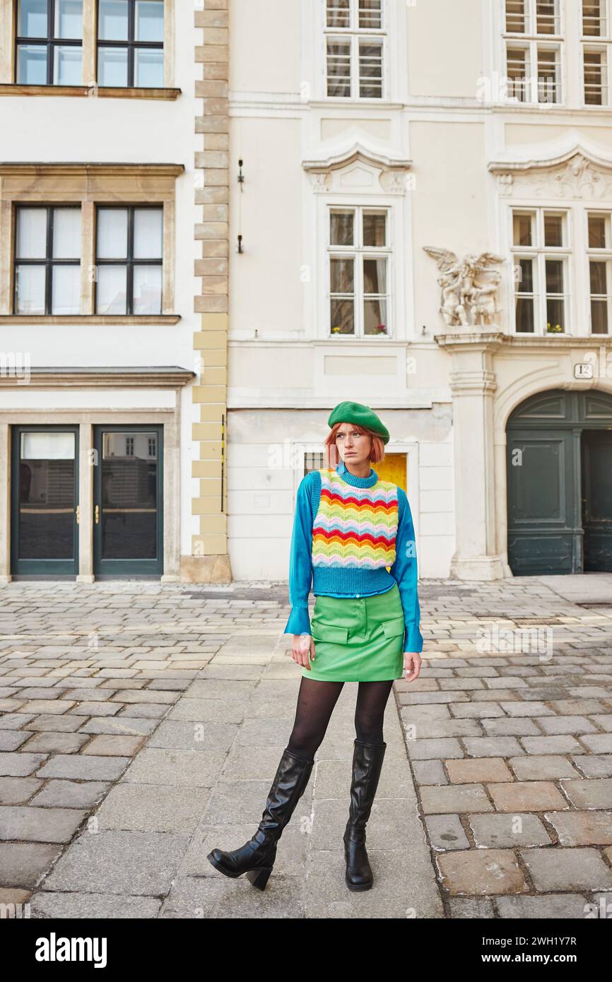 Style urbain, femme à la mode en béret et gilet lumineux regardant loin dans la rue à Vienne, Autriche Banque D'Images