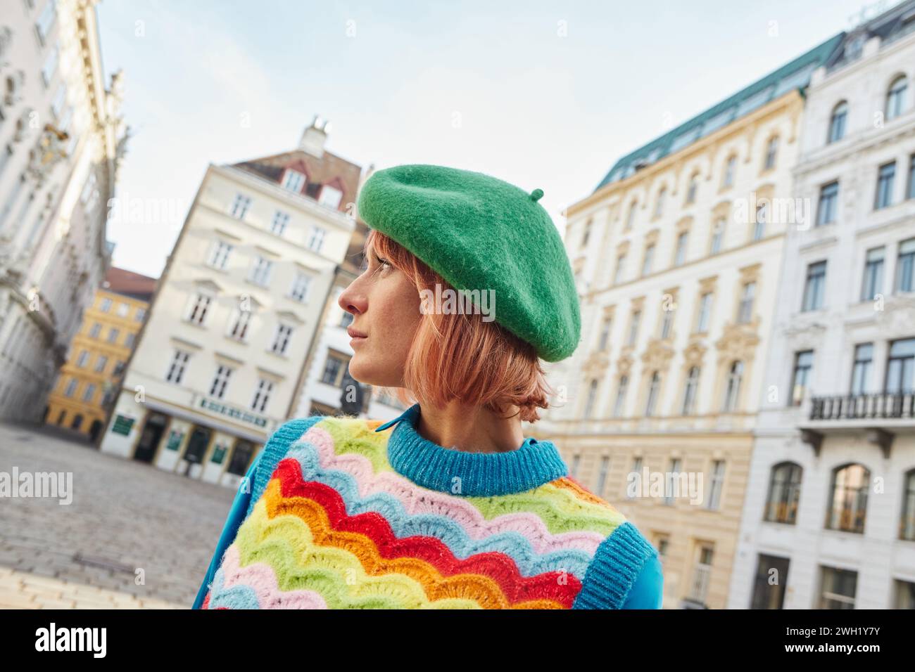Mode de rue moderne, femme élégante en béret et gilet lumineux regardant loin dans la rue à Vienne Banque D'Images