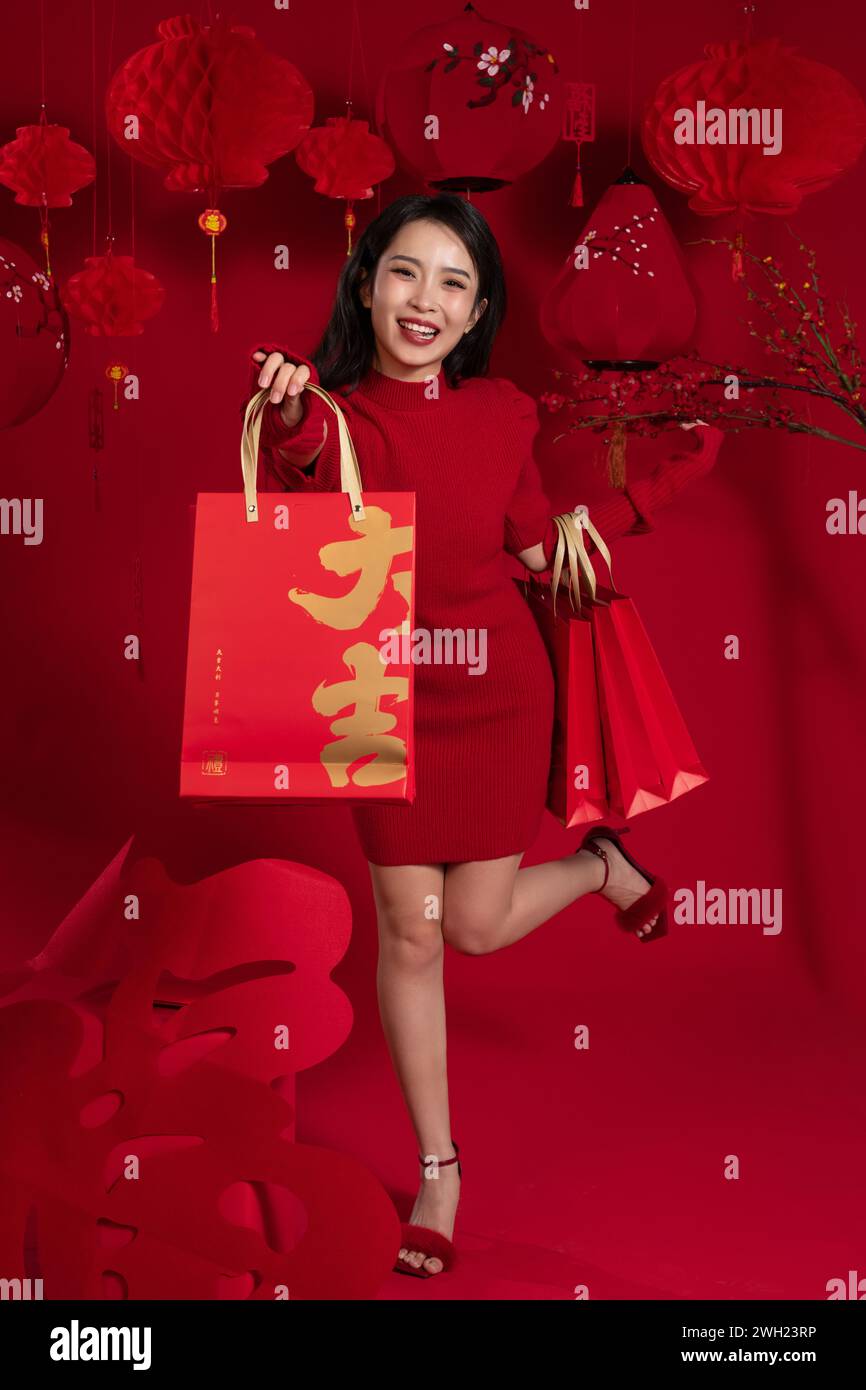 Shopping du nouvel an, une jeune femme asiatique tenant un sac à provisions sur fond rouge Banque D'Images