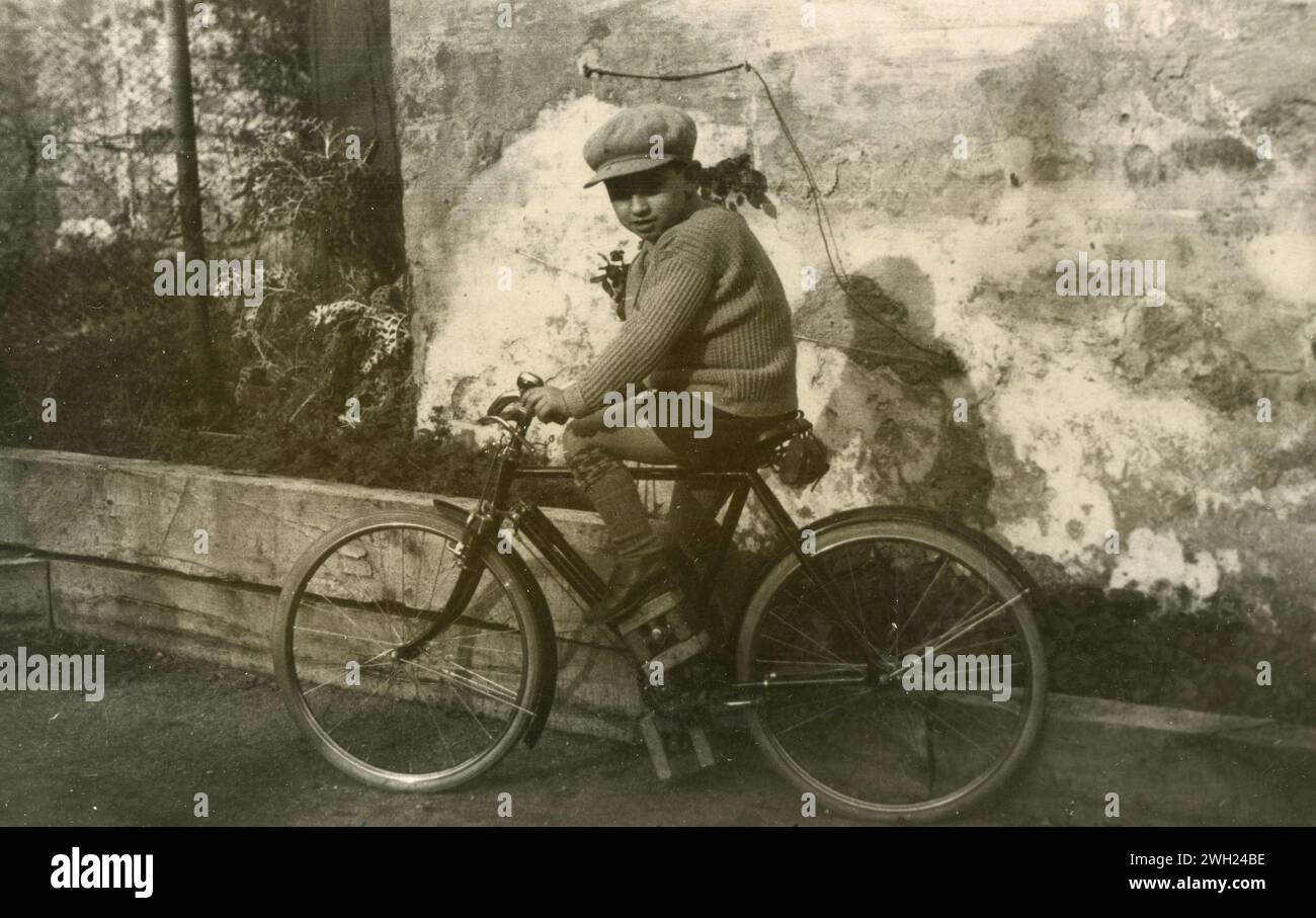 Enfant conduisant un grand vélo avec pédales modifiées, Italie 1933 Banque D'Images