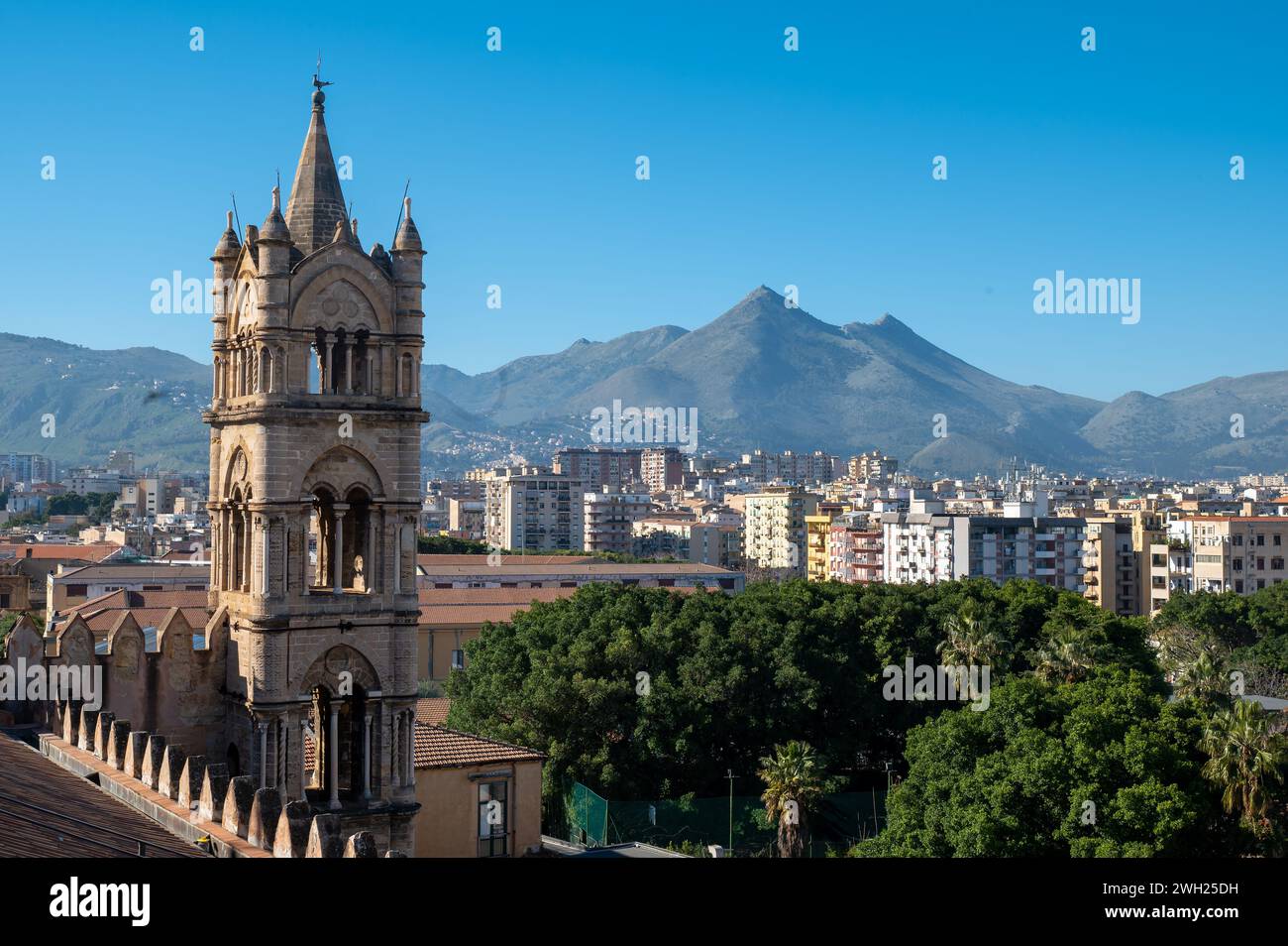 Une majestueuse cathédrale de Palerme se dresse au milieu d'un paysage époustouflant d'arbres, de montagnes et de la ville animée de palerme, en italie, ses imposantes flèches R Banque D'Images