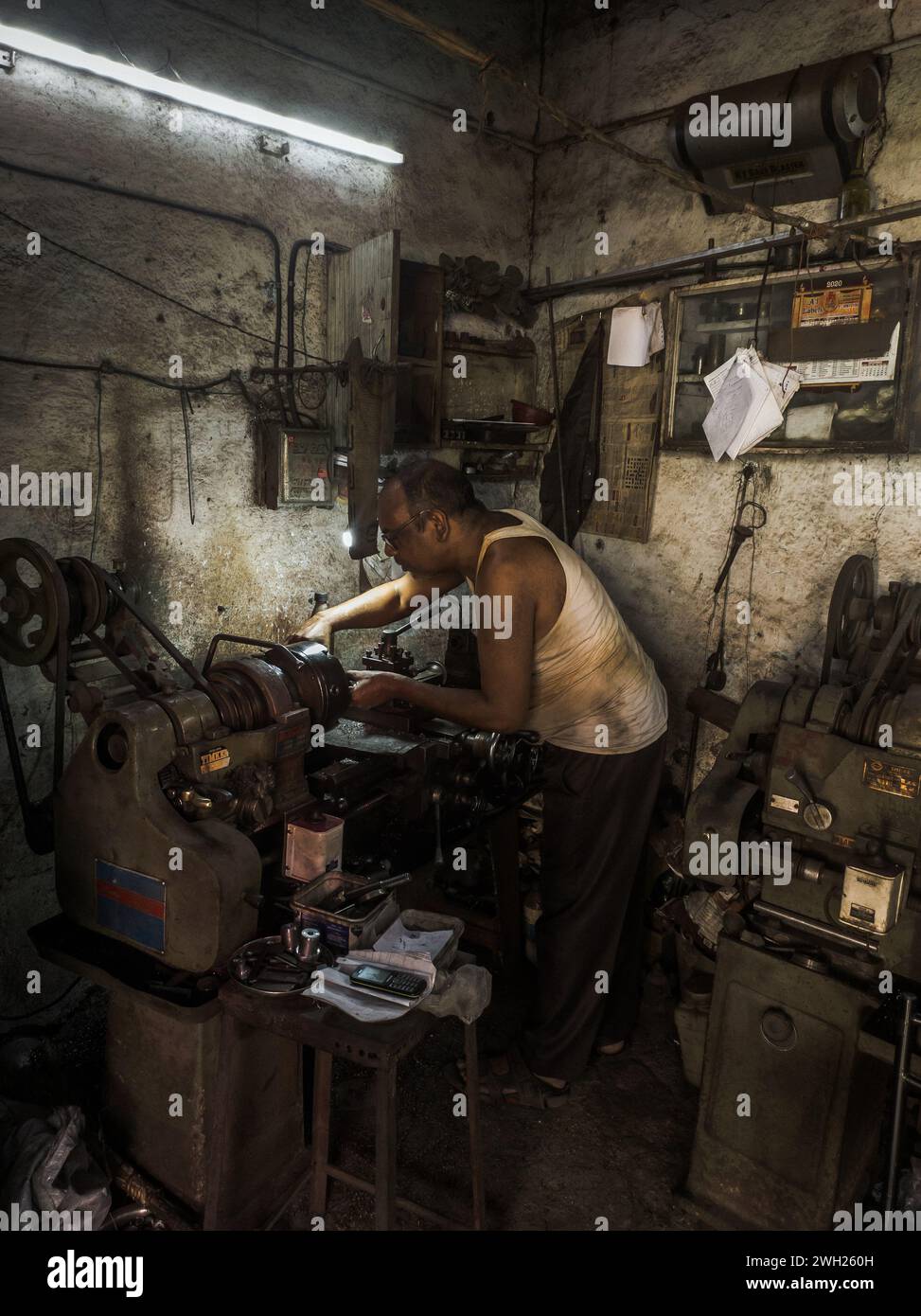 Un homme dans un atelier utilisant un assortiment d'outils et de matériaux Banque D'Images