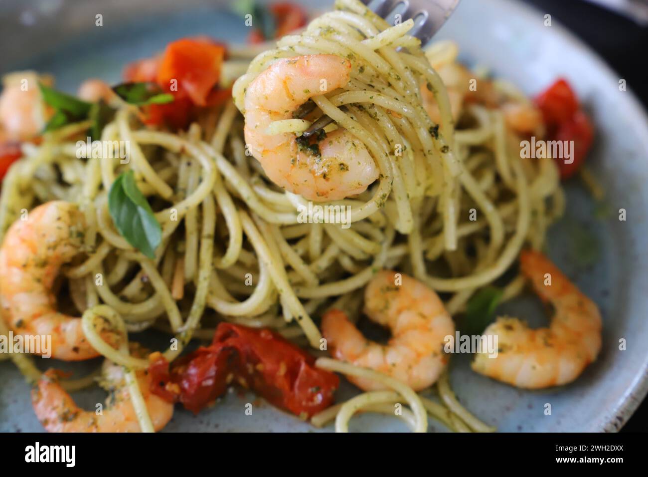 Un spaghetti au pesto, tomates confites et crevettes grillées. Banque D'Images