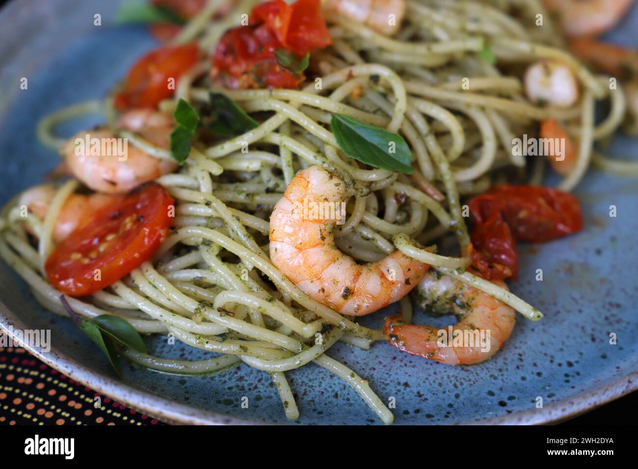 Un spaghetti au pesto, tomates confites et crevettes grillées. Banque D'Images