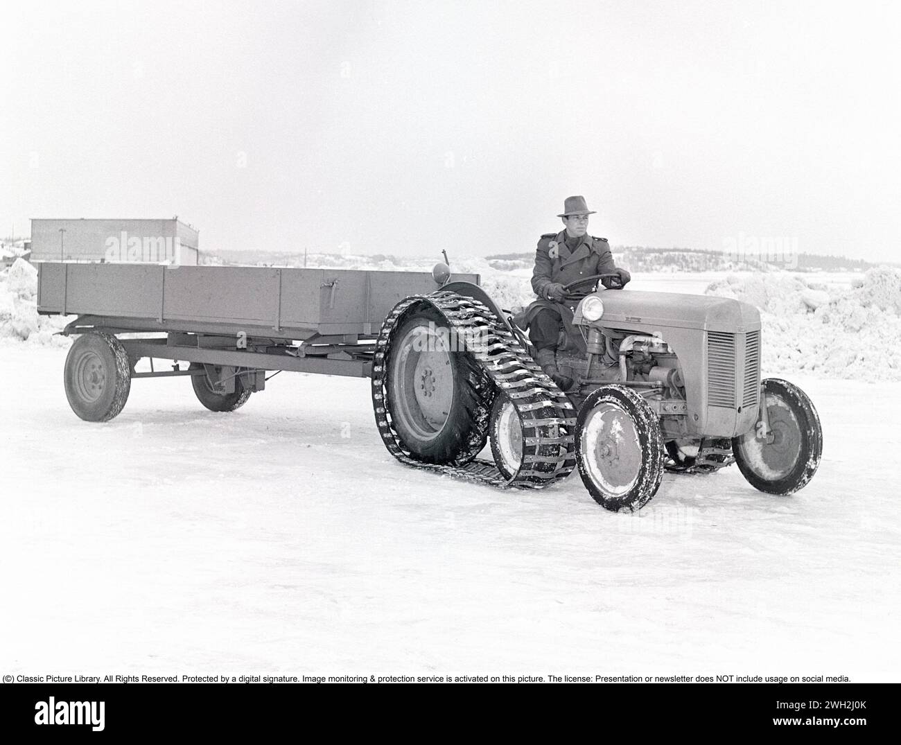 Tracteur Ferguson dans les années 1950 Un conducteur sur le légendaire tracteur Ferguson présenté avec des bracelets caterpillar et un wagon à un essieu derrière. Les tracteurs Ferguson ont été les premiers tracteurs agricoles modernes et leur système d'attelage à trois points a constitué un développement majeur. 1951. Kristoffersson ref BB46-4 Banque D'Images