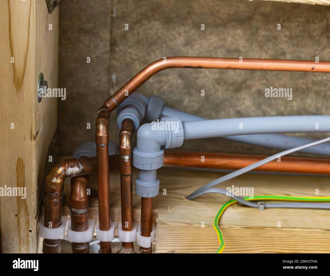 Divers tuyaux en cuivre et en plastique avec raccords pour l'eau chaude froide et le chauffage dans une maison domestique britannique Banque D'Images