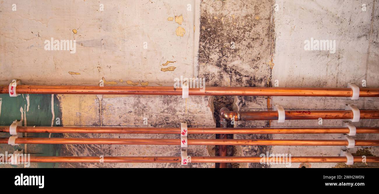 Tuyaux de gaz et d'eau en cuivre le long du mur avec des supports de fixation en plastique dans la rénovation de maison Royaume-Uni Banque D'Images