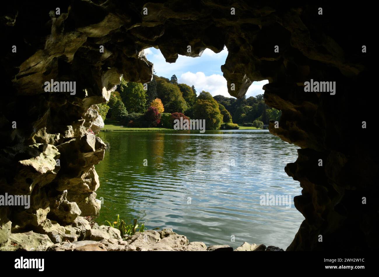 Couleurs d'automne dans les arbres de l'autre côté du lac à Stourhead dans le Wiltshire. Pris de l'intérieur de la grotte. Banque D'Images