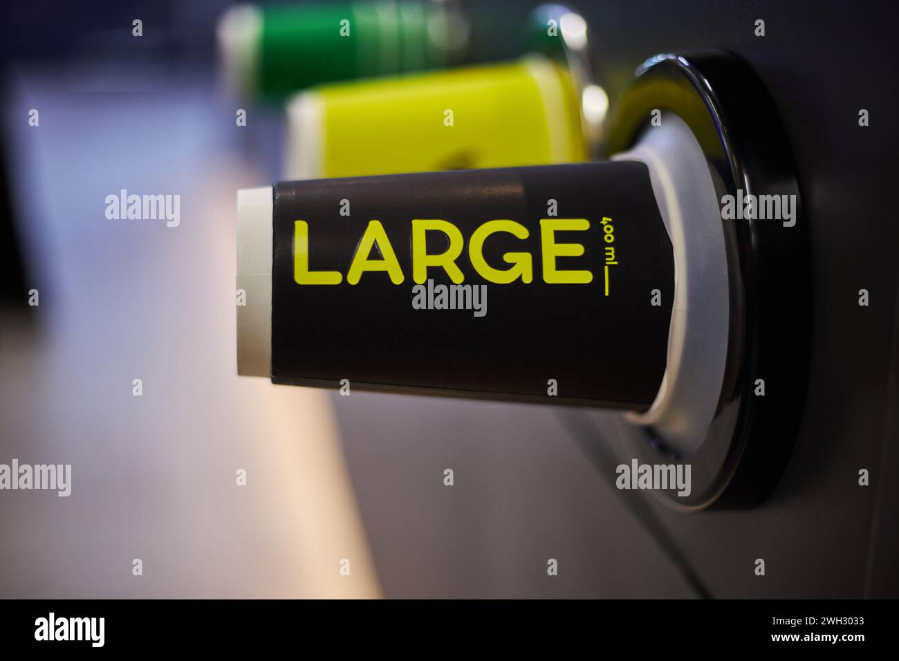 Café-restaurant, magasin, commerce de café. Gobelets en papier colorés, noir grand, jaune moyen, vert petite tasse différentes tailles pour les boissons chaudes café, thé à prendre Banque D'Images