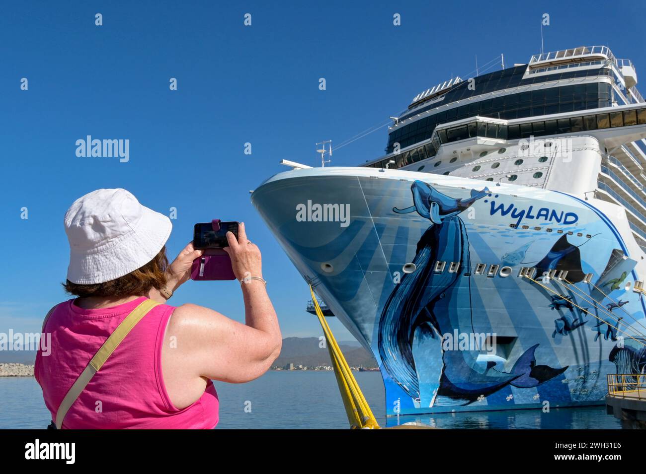 Manzanillo, Mexique - 16 janvier 2024 : passager d'un bateau de croisière prenant une photo du paquebot norvégien Bliss sur un téléphone portable Banque D'Images