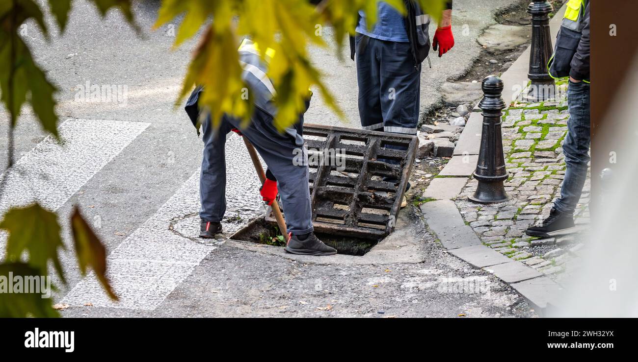 Groupe de travailleurs méconnaissables réparent la rue, effectuant des tâches pour entretenir et améliorer la route et le drainage des eaux usées. Banque D'Images