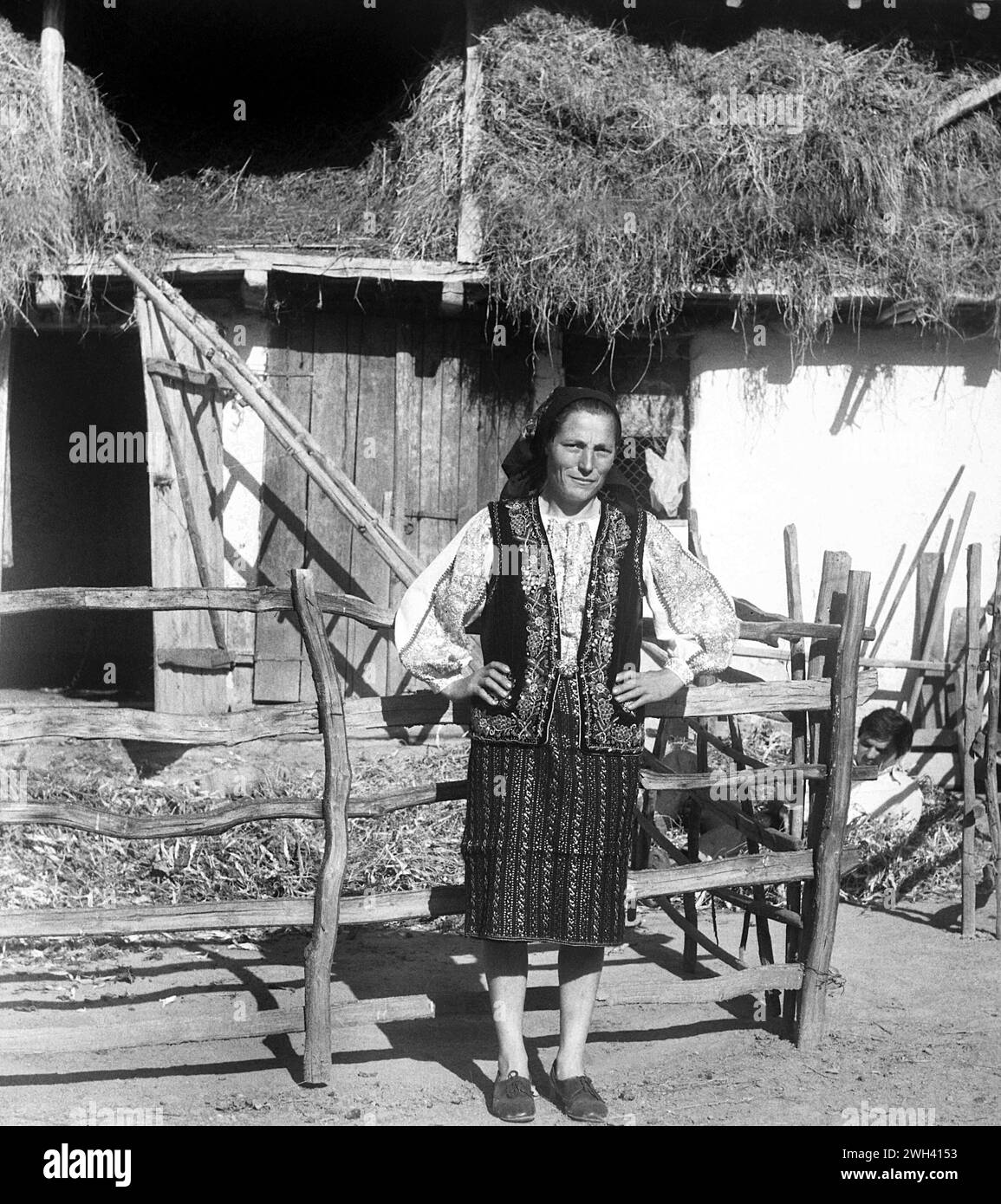 Comté de Vrancea, République socialiste de Roumanie, approx. 1975. Femme dans sa cour portant de beaux vêtements traditionnels. Banque D'Images