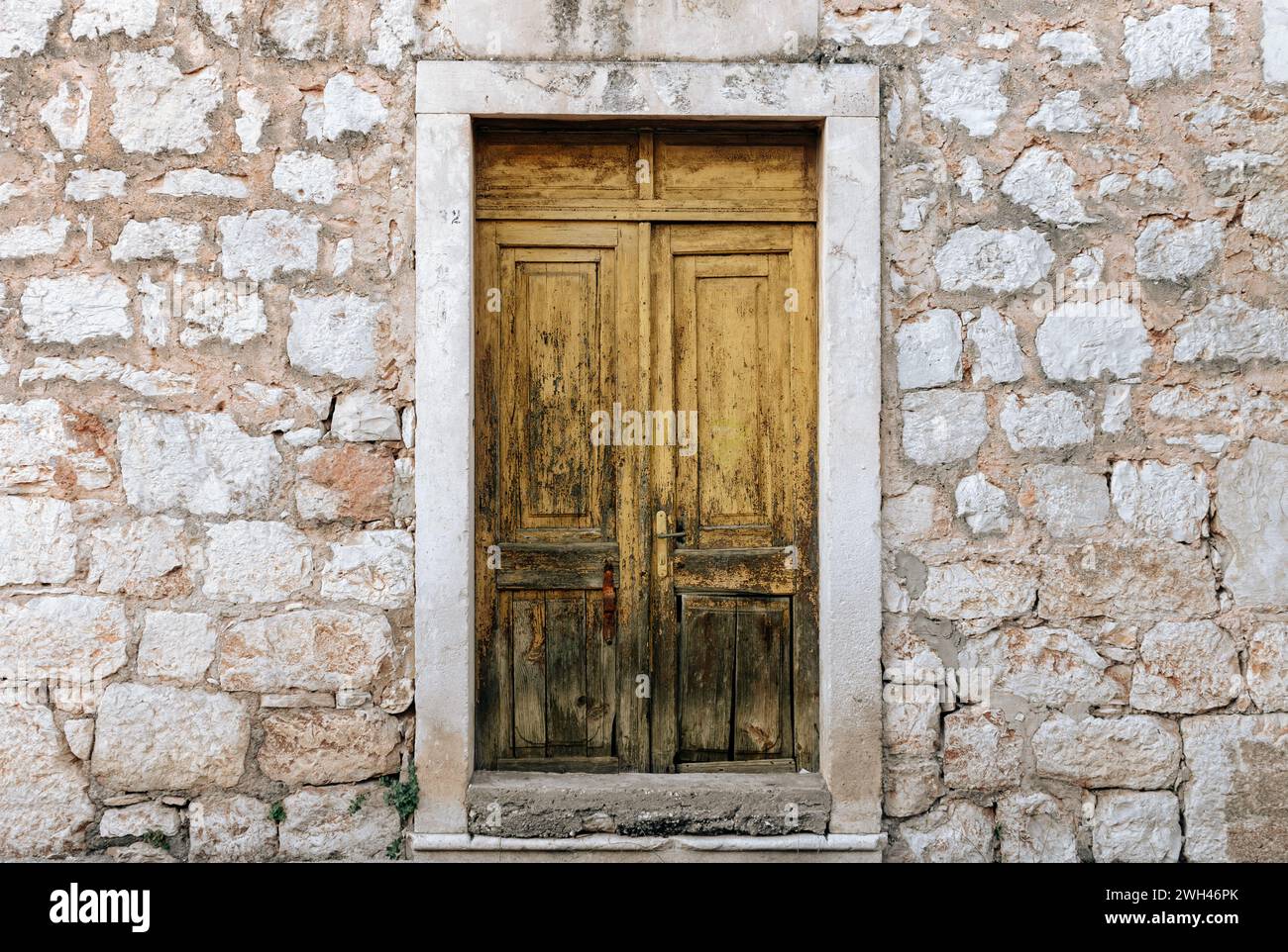 Porte en bois jaune rustique sur la vieille maison en pierre Banque D'Images