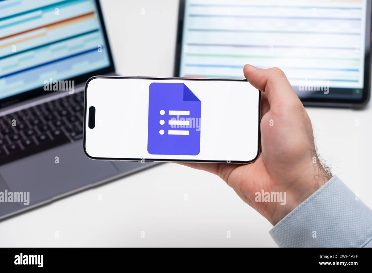 PRAGUE, RÉPUBLIQUE TCHÈQUE - 21 JANVIER 2024:logo Google Docs sur l'écran d'un téléphone portable dans la main des hommes d'affaires et ordinateur portable sur le fond. Banque D'Images