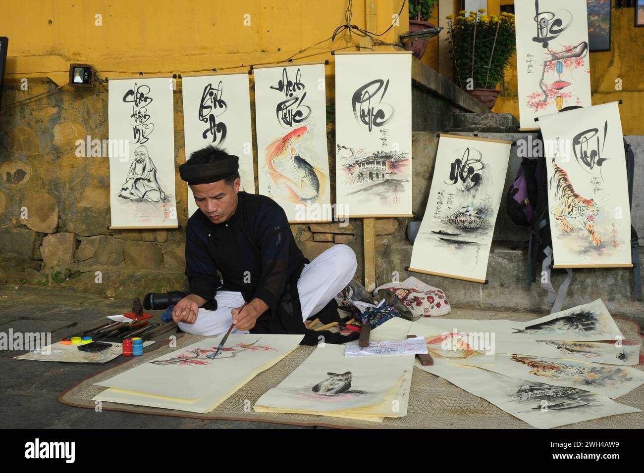Artiste dessine la calligraphie vietnamienne près du pont couvert japonais à Hoi an, Vietnam Banque D'Images
