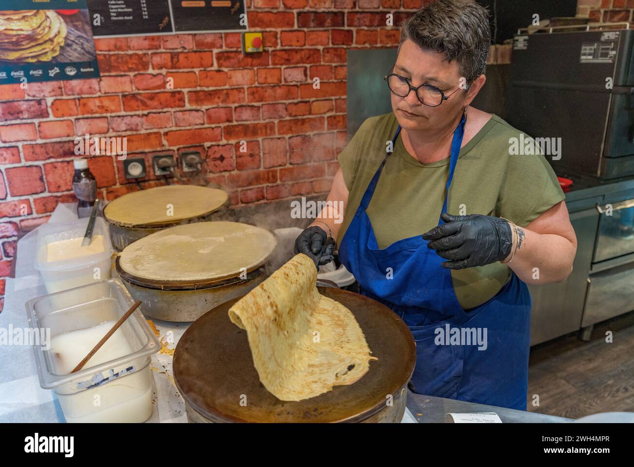 Une femme fabriquant des crêpes au Mont Saint Michel en Normandie, France Banque D'Images