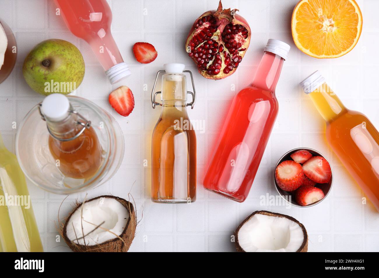 Savoureux kombucha dans des bouteilles en verre et fruits frais sur table carrelée blanche, pose à plat Banque D'Images