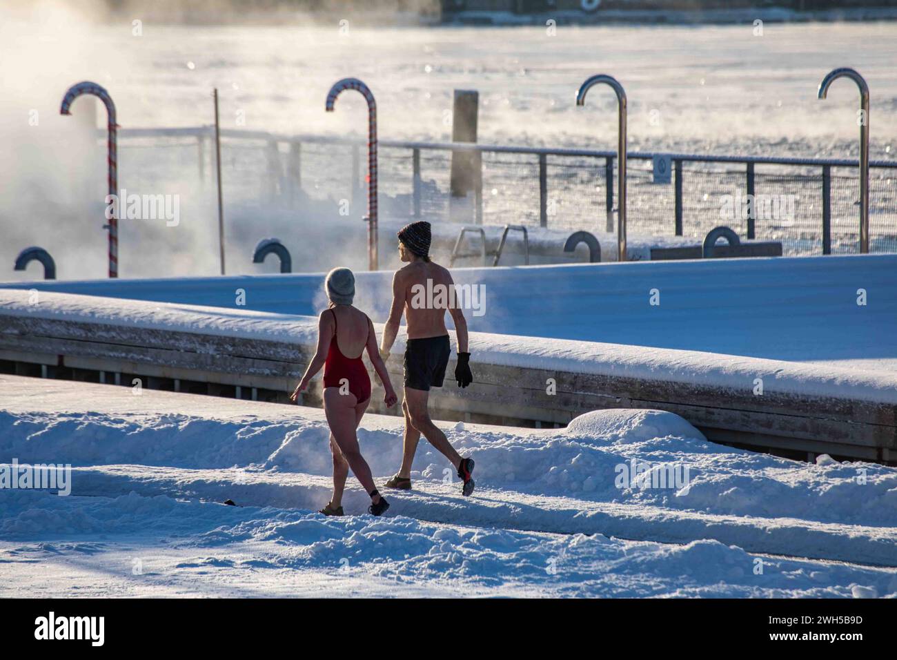 Un couple de vapeur se rafraîchissant après un sauna sur la terrasse couverte de neige de la piscine de la mer Allas lors d'une froide journée d'hiver à Helsinki, en Finlande Banque D'Images
