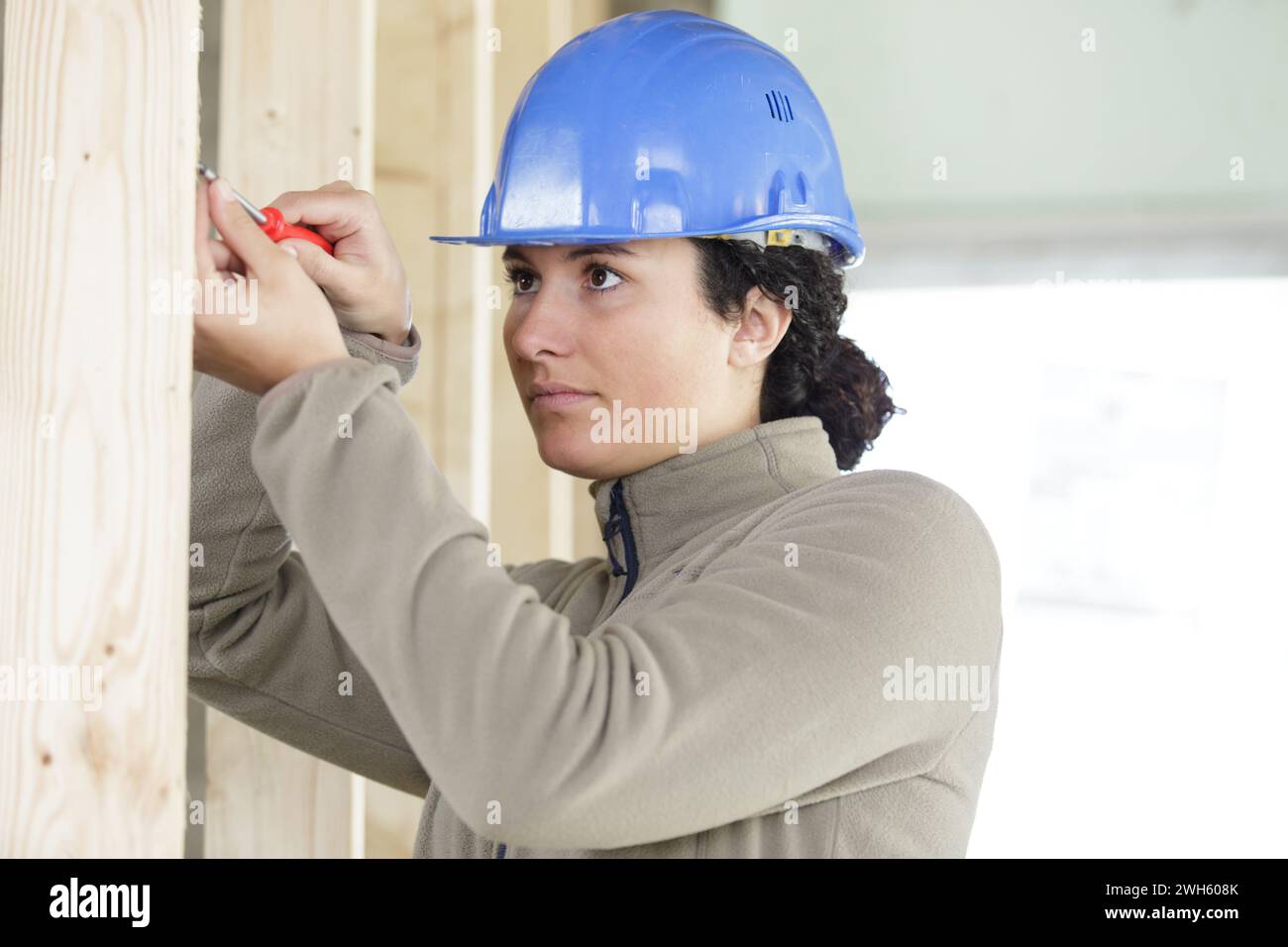 femme à tout faire concentrée tenant des planches de bois Banque D'Images