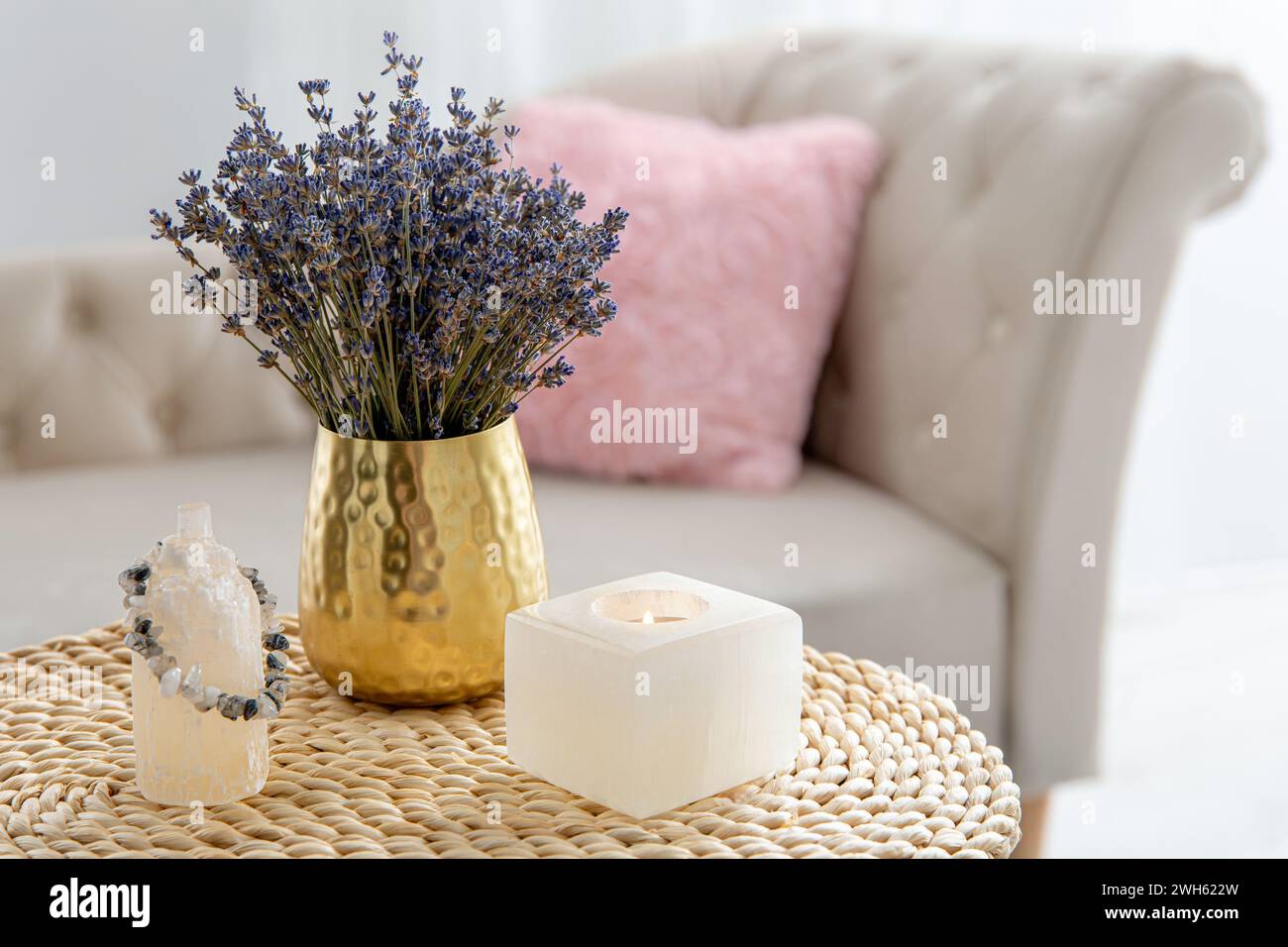 Bougeoir en cristal de sélénite et tour pour une bonne énergie, fleur de lavande sèche dans le vase dans le salon de la maison de couleur claire, canapé avec oreiller rose. Banque D'Images